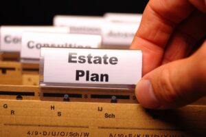 Close-up of a hand placing a label that reads Estate Plan on a filing surface, conveying planning or legal documents.