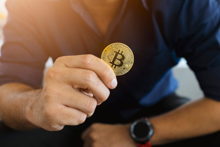 golden bitcoin in a businessman hand in the office with soft focus and backlighting. cryptocurrency concept | Houlihan Capital