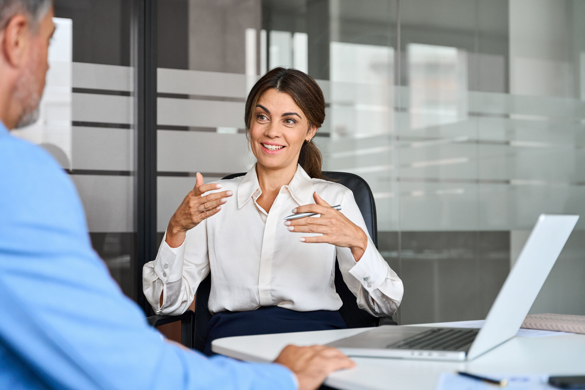 Happy female professional bank manager consulting client at office meeting. | Houlihan Capital Happy female professional bank manager discussing micro middle market intelligence at office meeting.