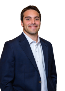 Smiling man in a navy blazer and white shirt, portrait against a white background