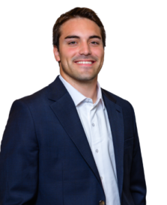 Professional headshot of a smiling man in a navy suit and white shirt against a white background.