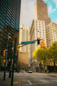 Downtown street scene with tall beige and glass towers, a blue Luckie St NW sign, and a traffic light intersection.