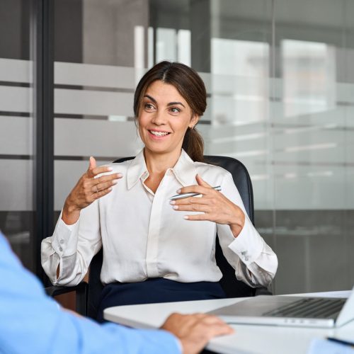 Happy female professional bank manager discussing micro middle market intelligence at office meeting.